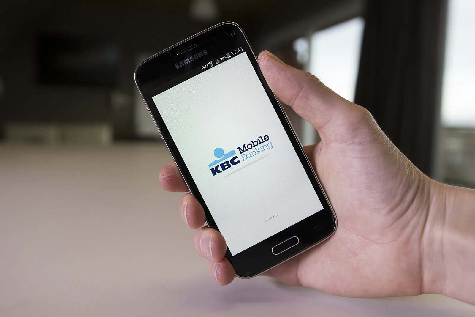 Hand houdt een telefoon vast met de app KBC Mobile Banking